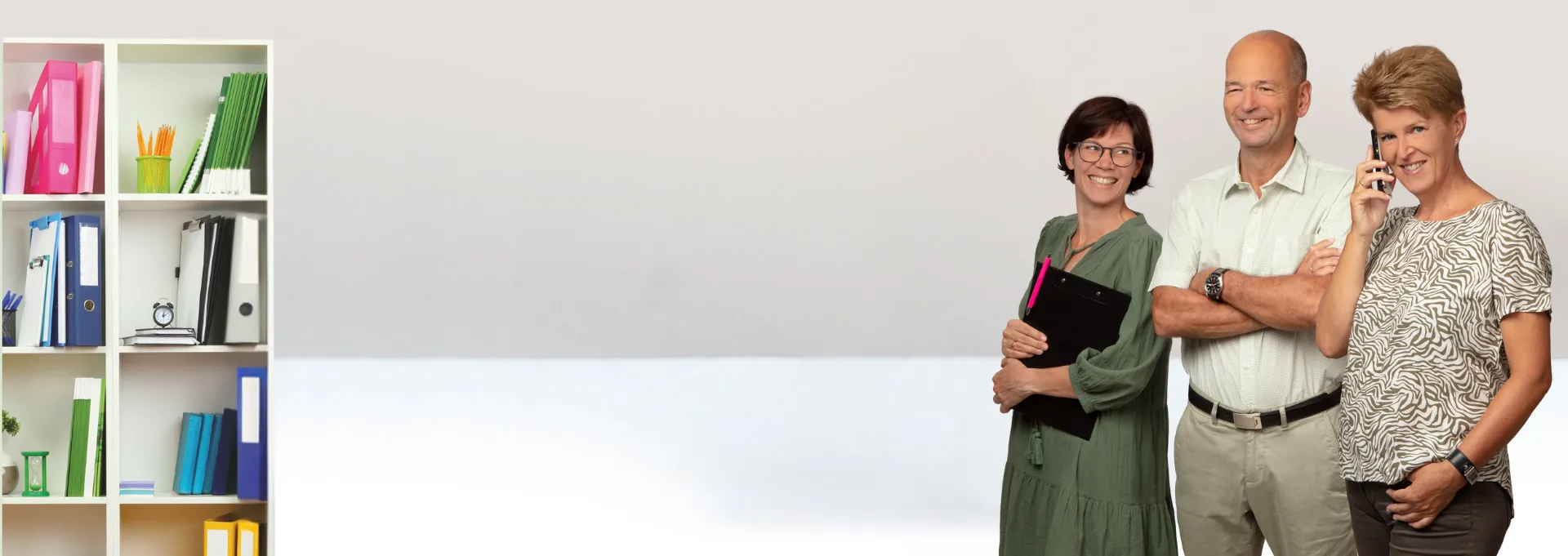 Doris Gaspari telefoniert mit Team im Hintergrund und Regal mit Ordnern links im Bild